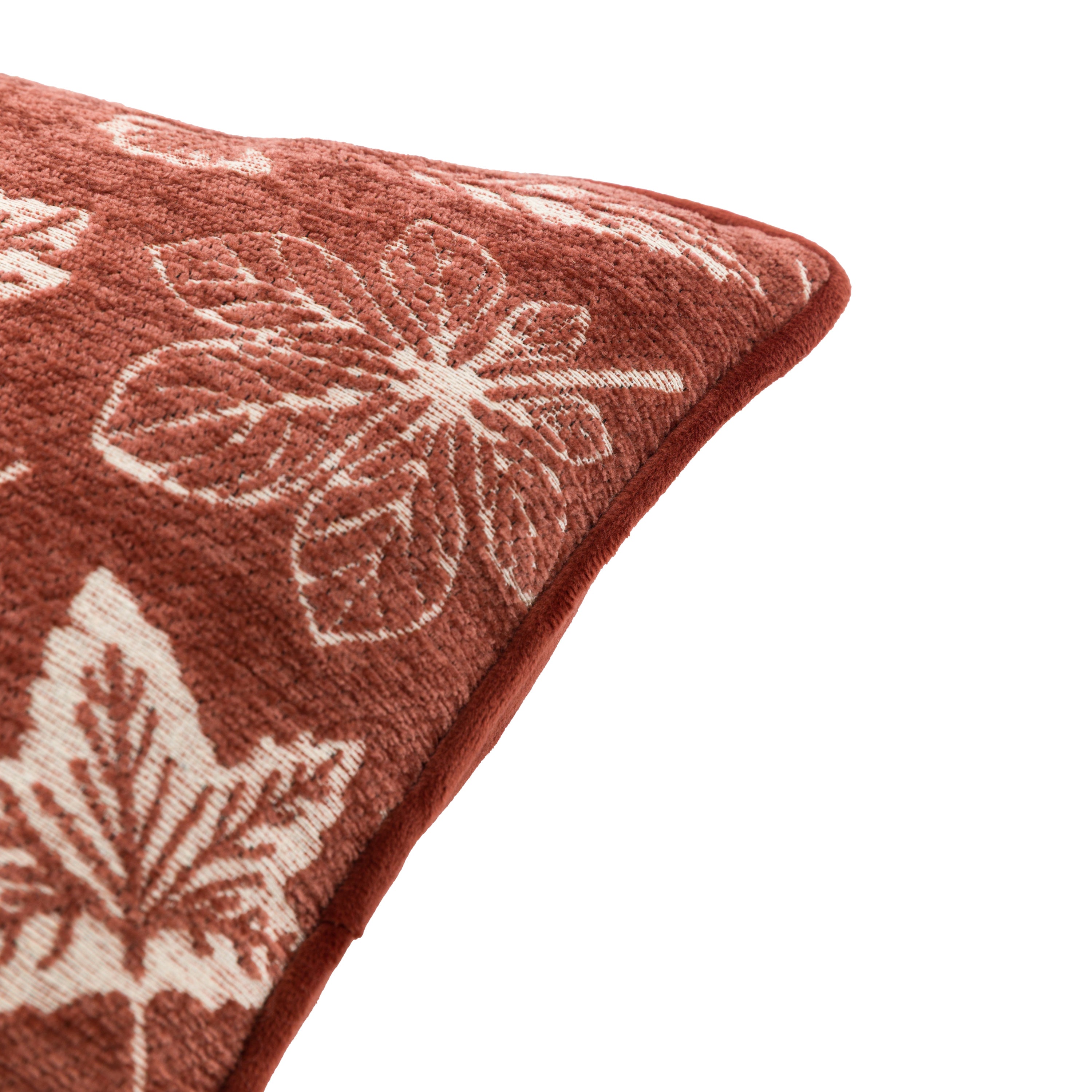 A close-up shot of the corner of the rust-colored cushion with leaf designs.