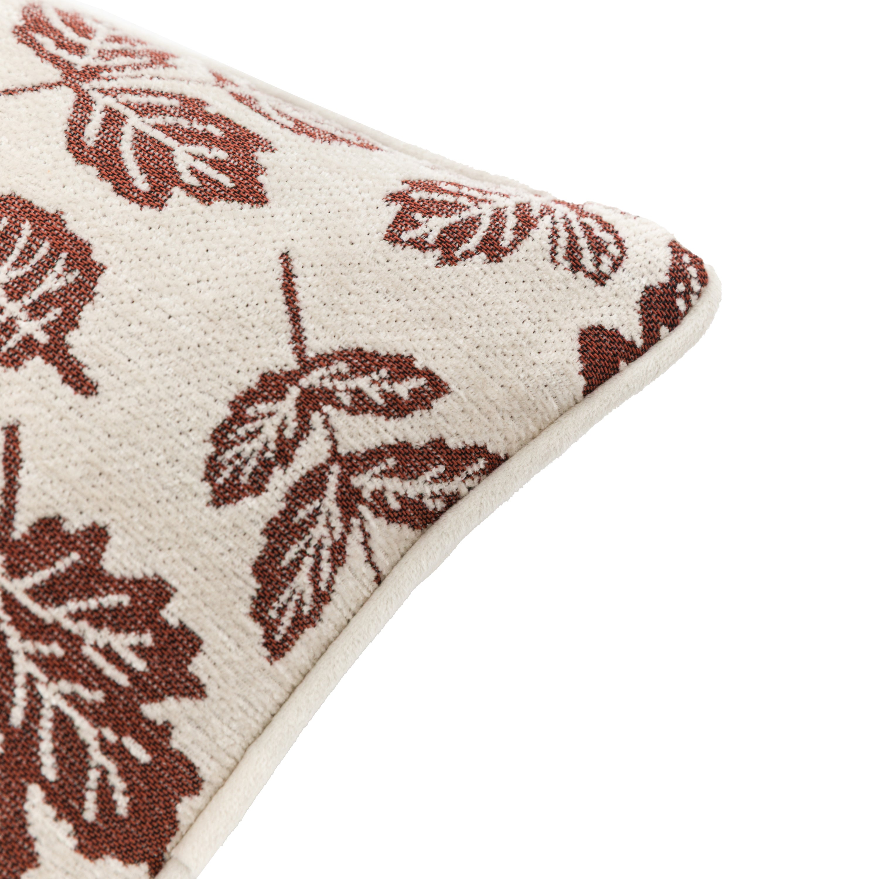 A close-up of the corner of a cushion with a red leaf pattern.