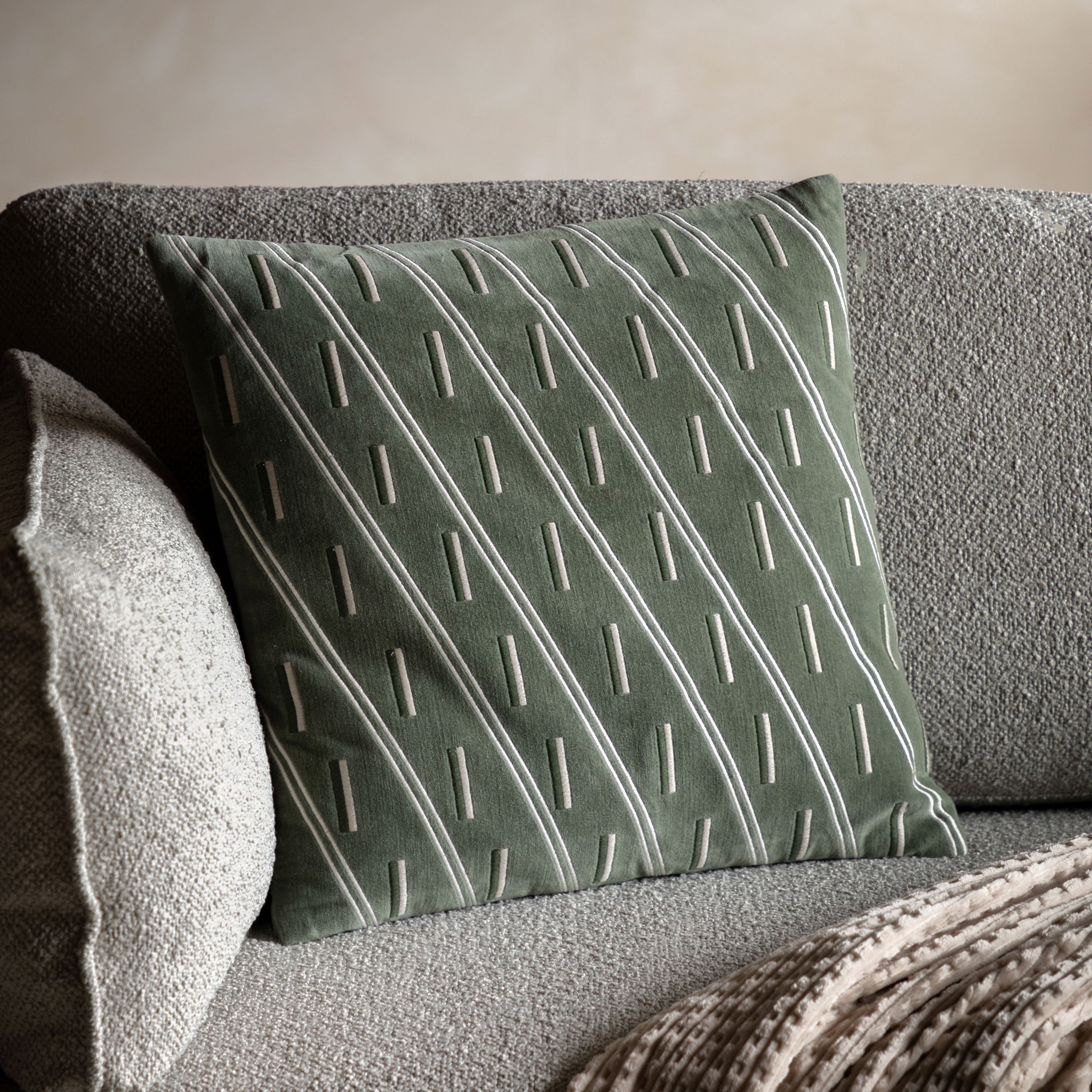 Textured olive green pillow on a grey sofa.