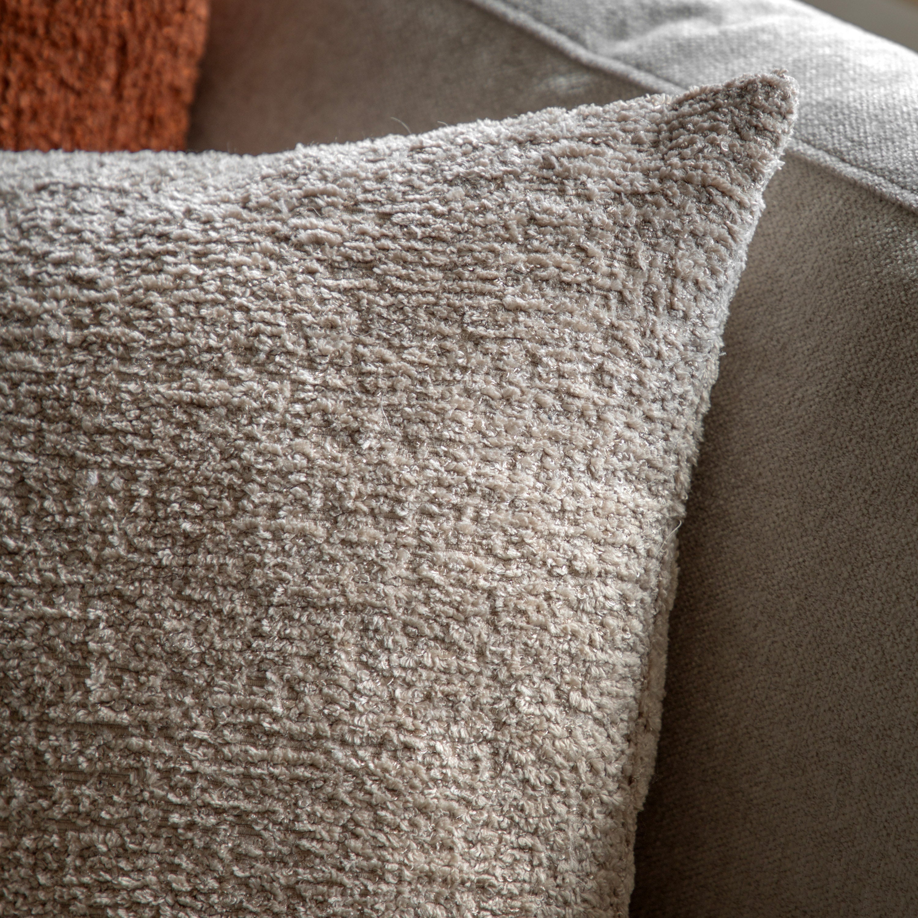 A close-up view of a grey bouclé throw pillow, highlighting its textured fabric.