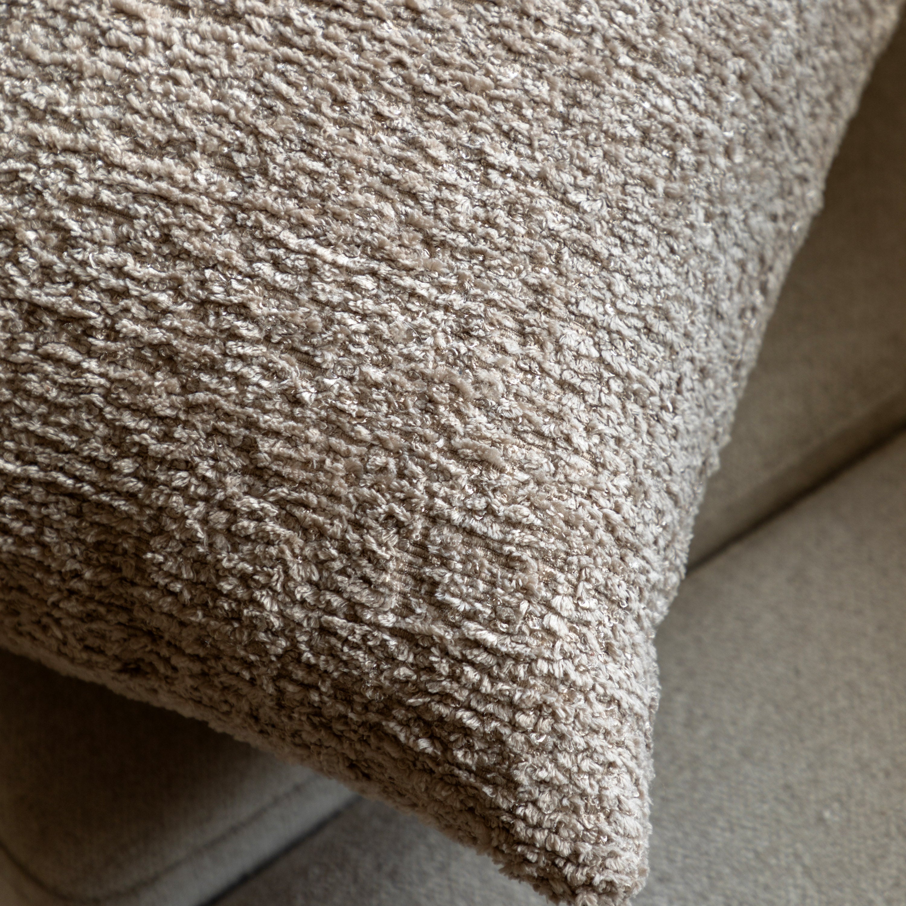 A close-up shot of the textured grey bouclé fabric of a throw pillow.