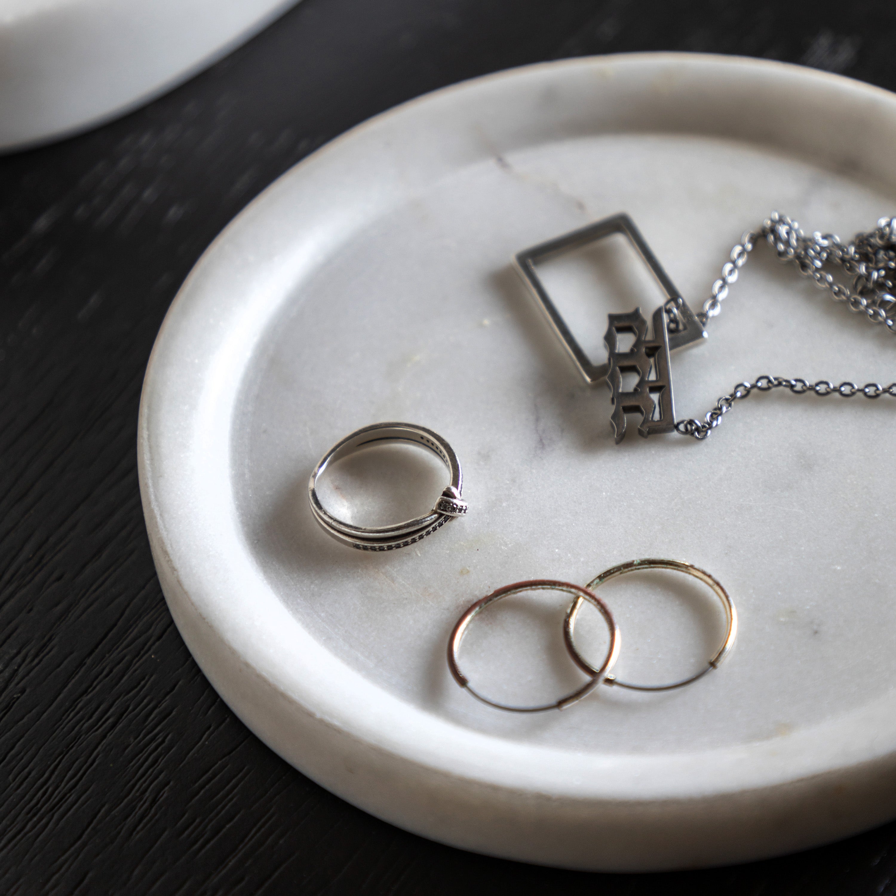 A small marble tray holds a necklace and several rings.