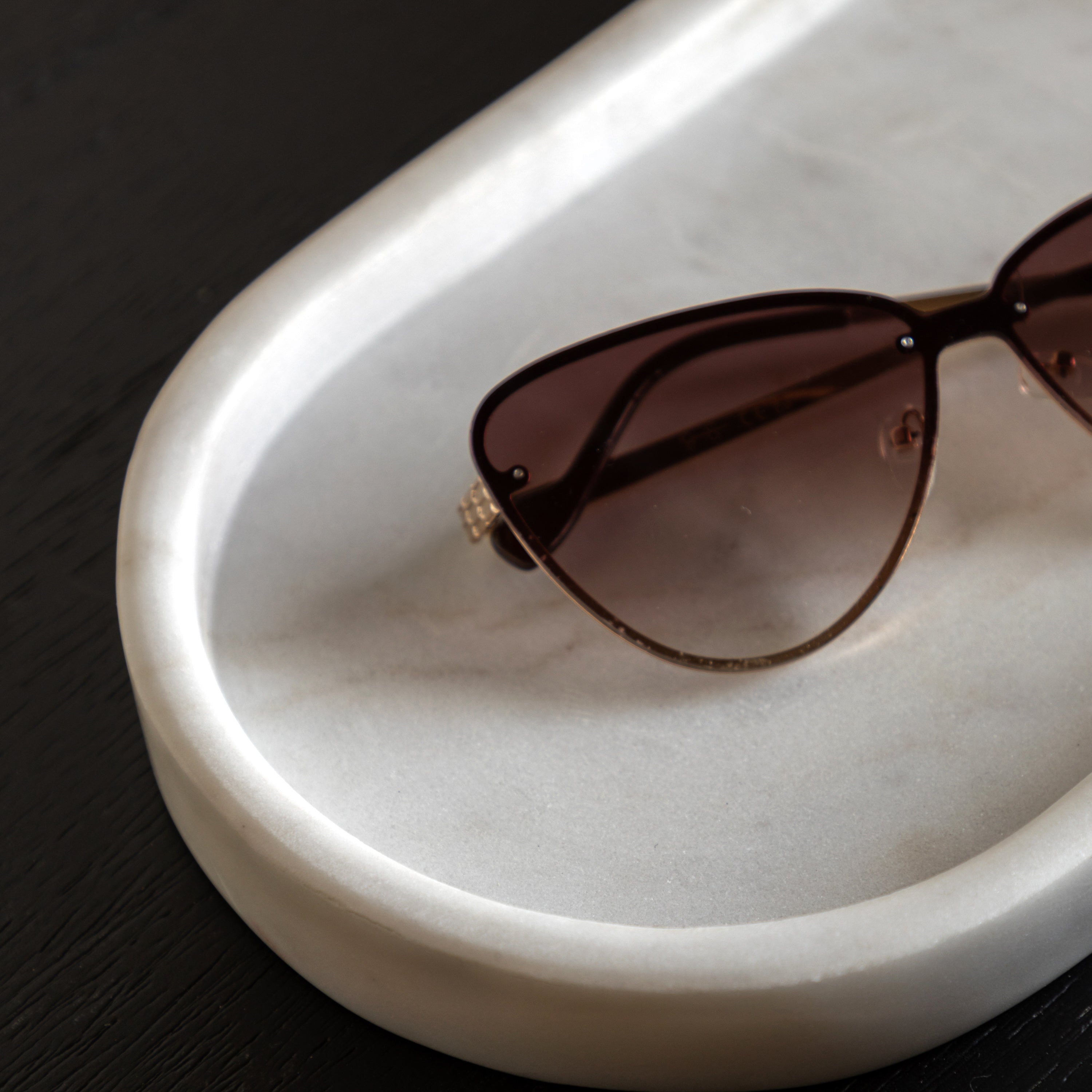 A large marble tray holds a pair of sunglasses.
