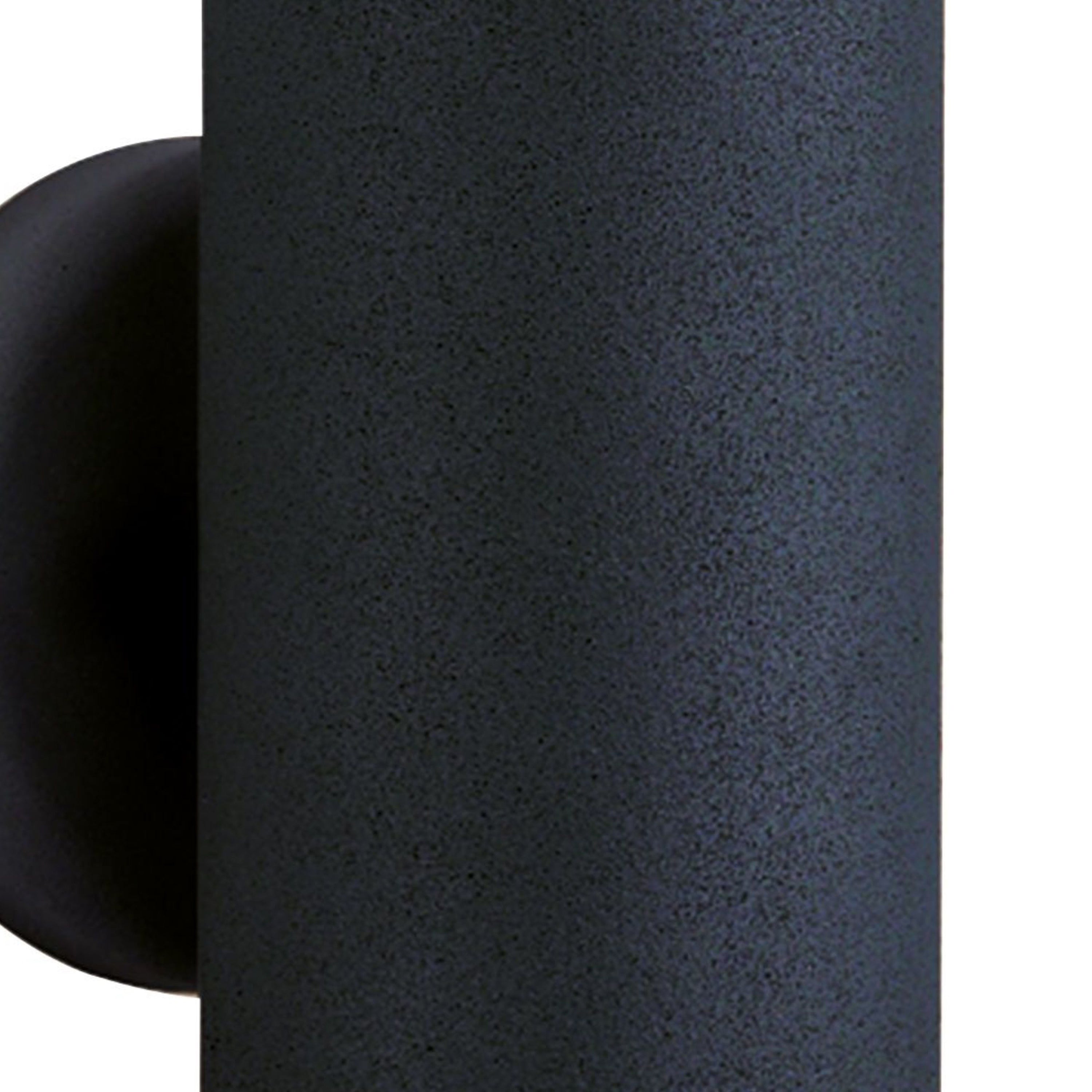 A close-up of the textured black finish of a cylindrical outdoor wall light.