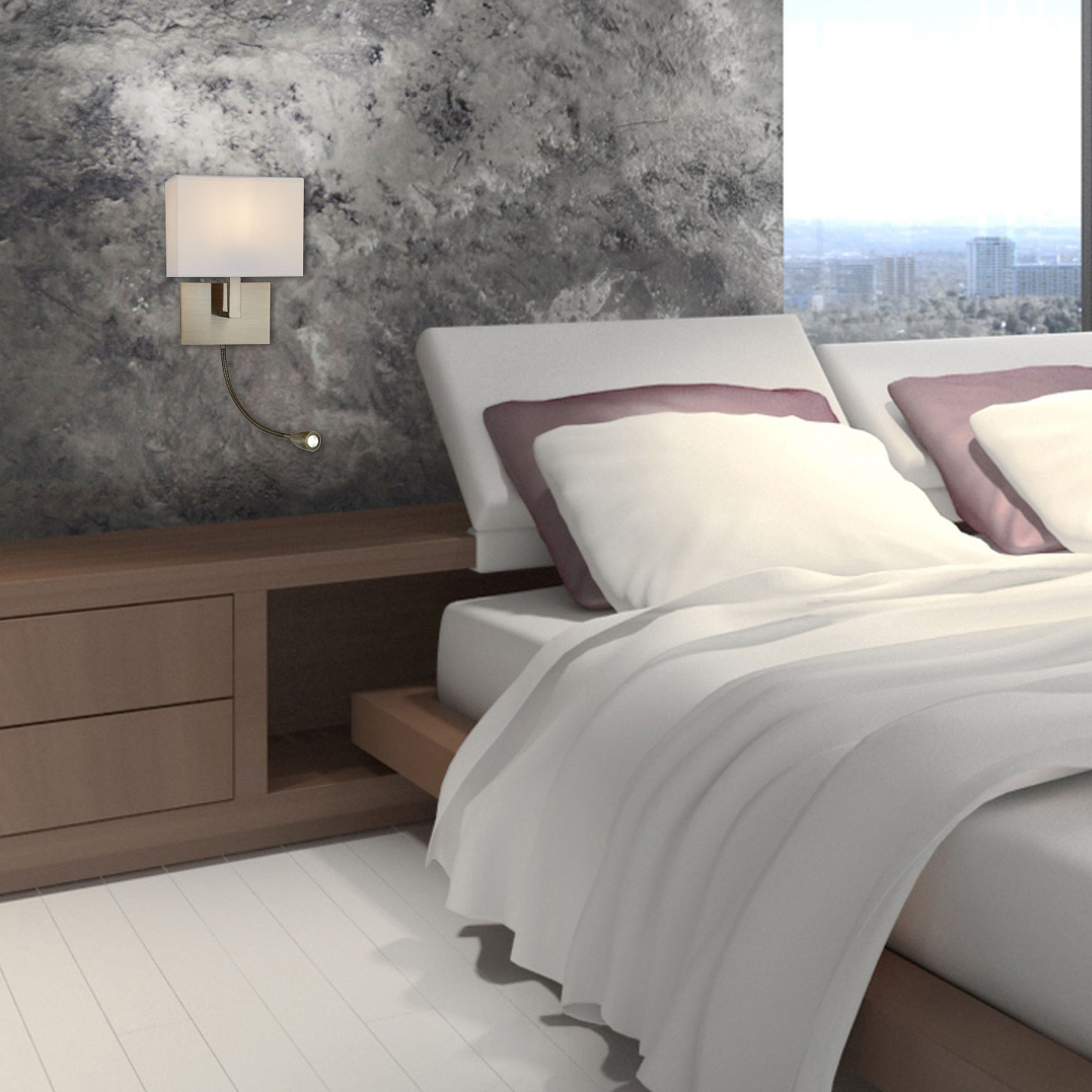 A modern brass wall light illuminates a stylish bedroom with a large bed and bedside table.