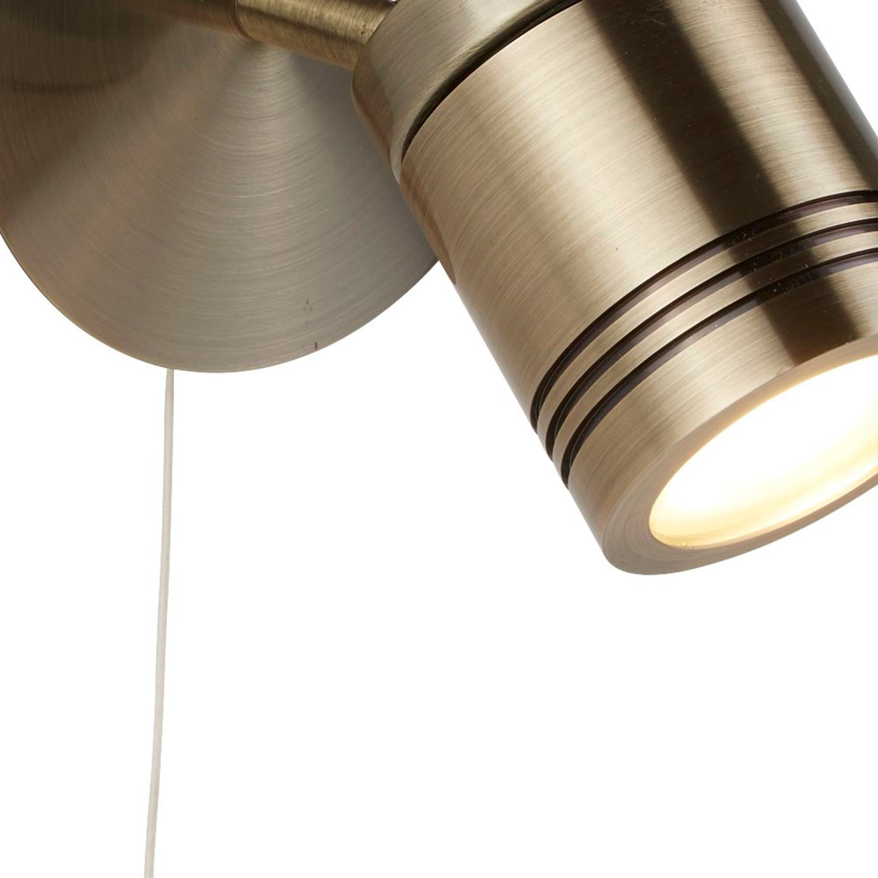 Close-up of a brass spotlight with a pull cord, highlighting its textured finish.