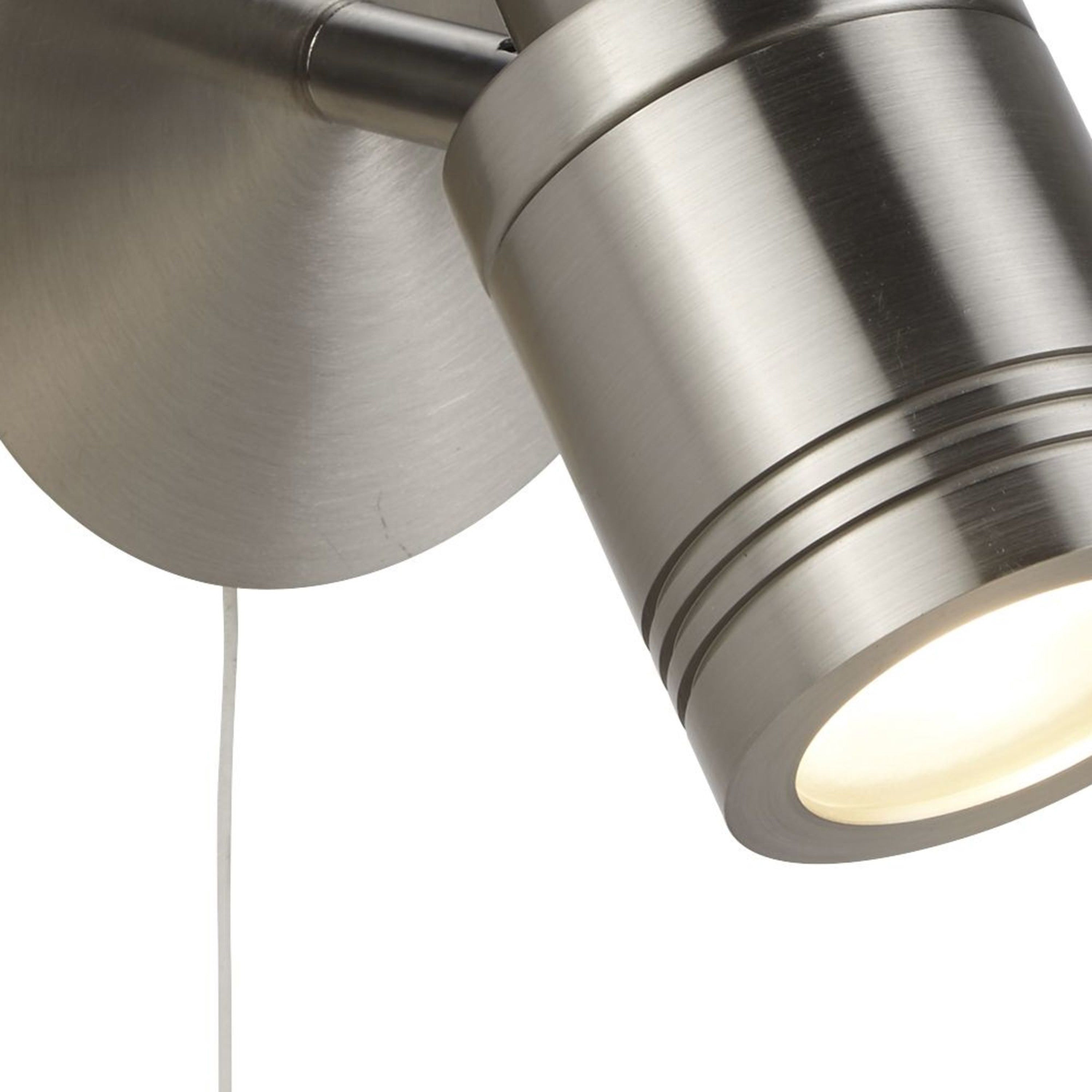 A close-up of a brushed steel wall light with an illuminated, directional spotlight.