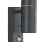A close-up of a black outdoor wall light with two cylindrical lights and a small sensor.