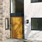 Black outdoor wall light installed on a modern white house exterior with a wooden door.