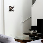 A modern living room with a unique wall sconce on a white wall above a glass table.