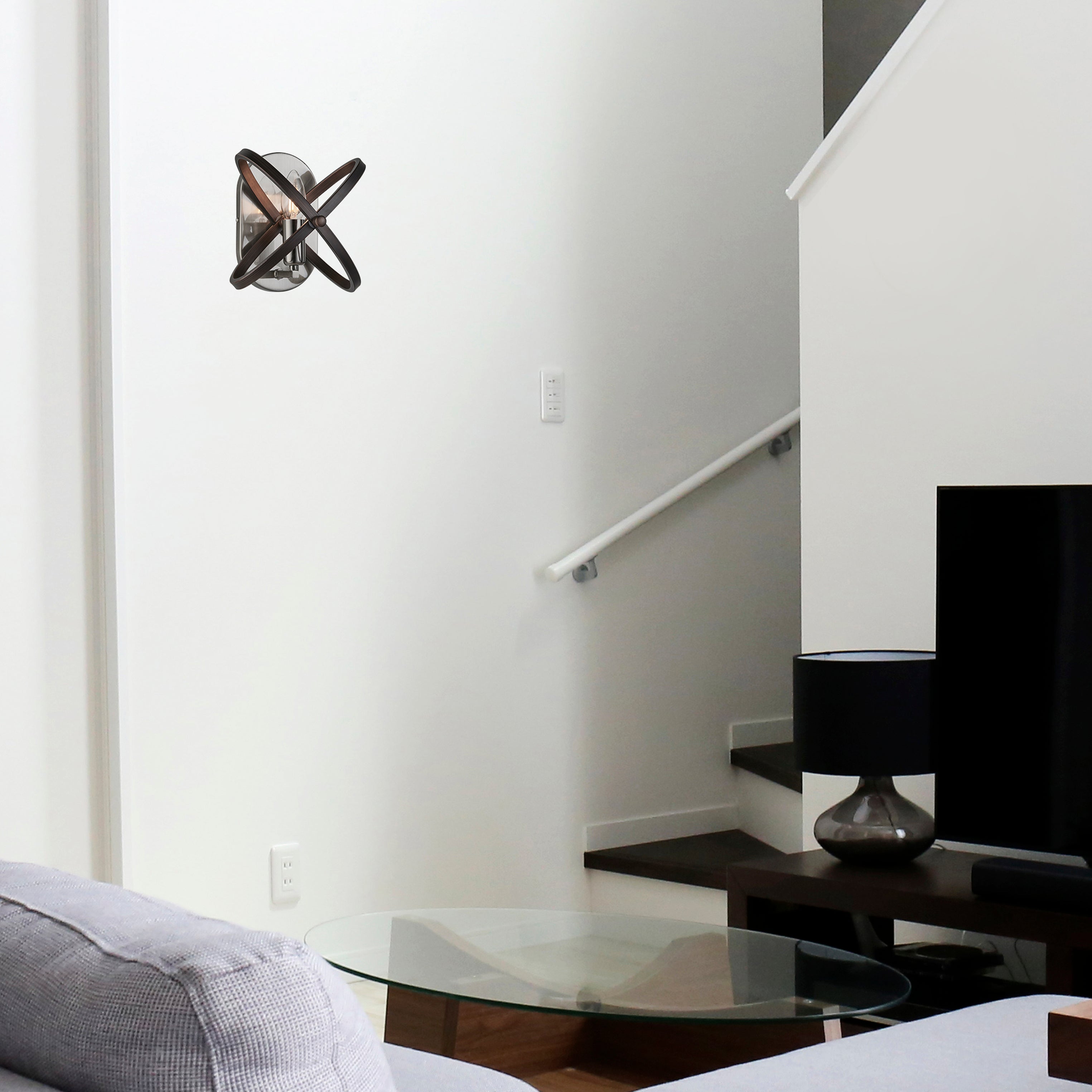 A modern living room with a unique wall sconce on a white wall above a glass table.