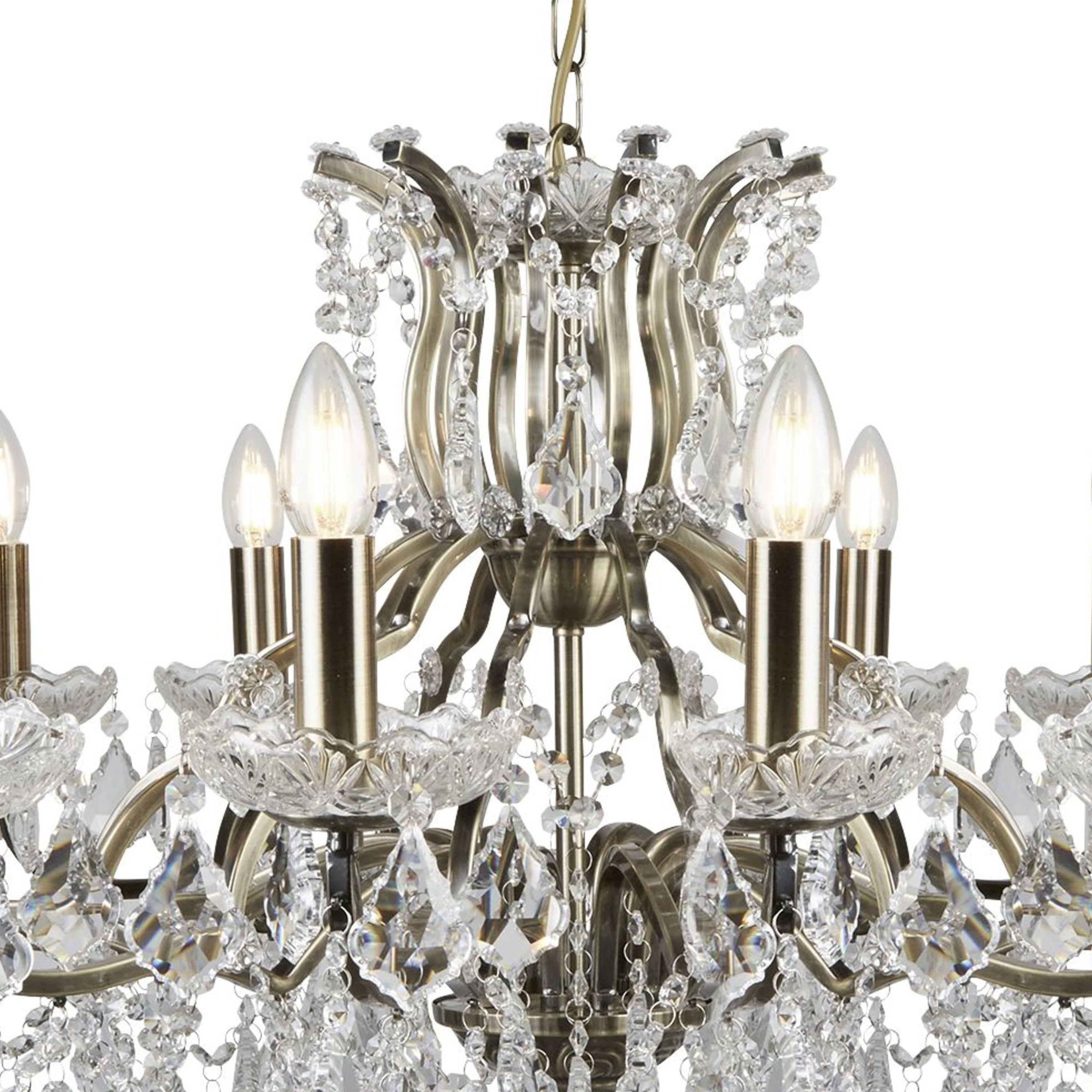 A close-up of a 12-light crystal chandelier with a brass finish.