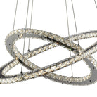 Close-up of a modern crystal LED pendant light, showing two intertwined, crystal-studded rings.