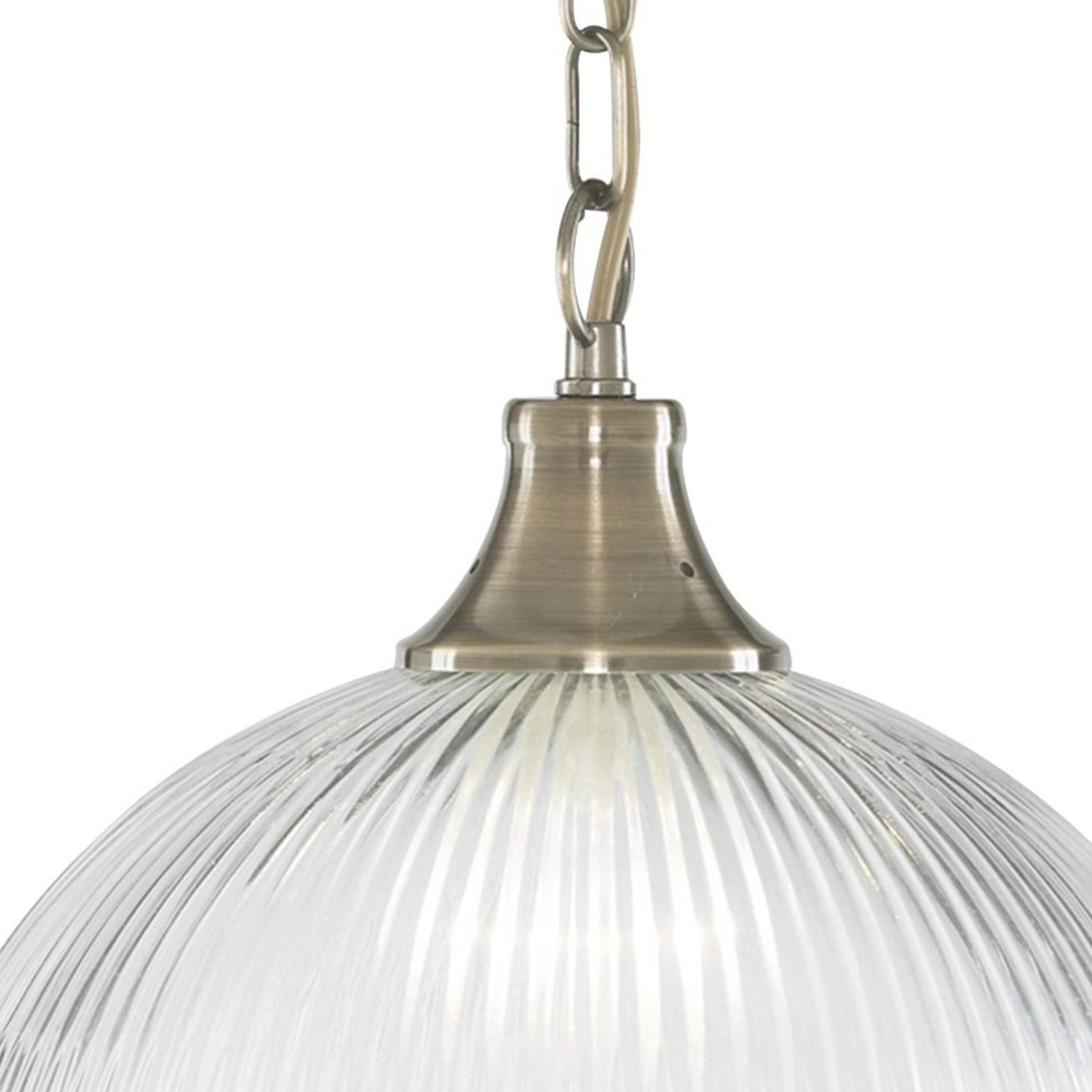 Close-up of a clear ribbed glass dome pendant light with an antique brass fixture.