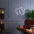 Modern chrome pendant light with an Eames chair and bookshelf in a living room.