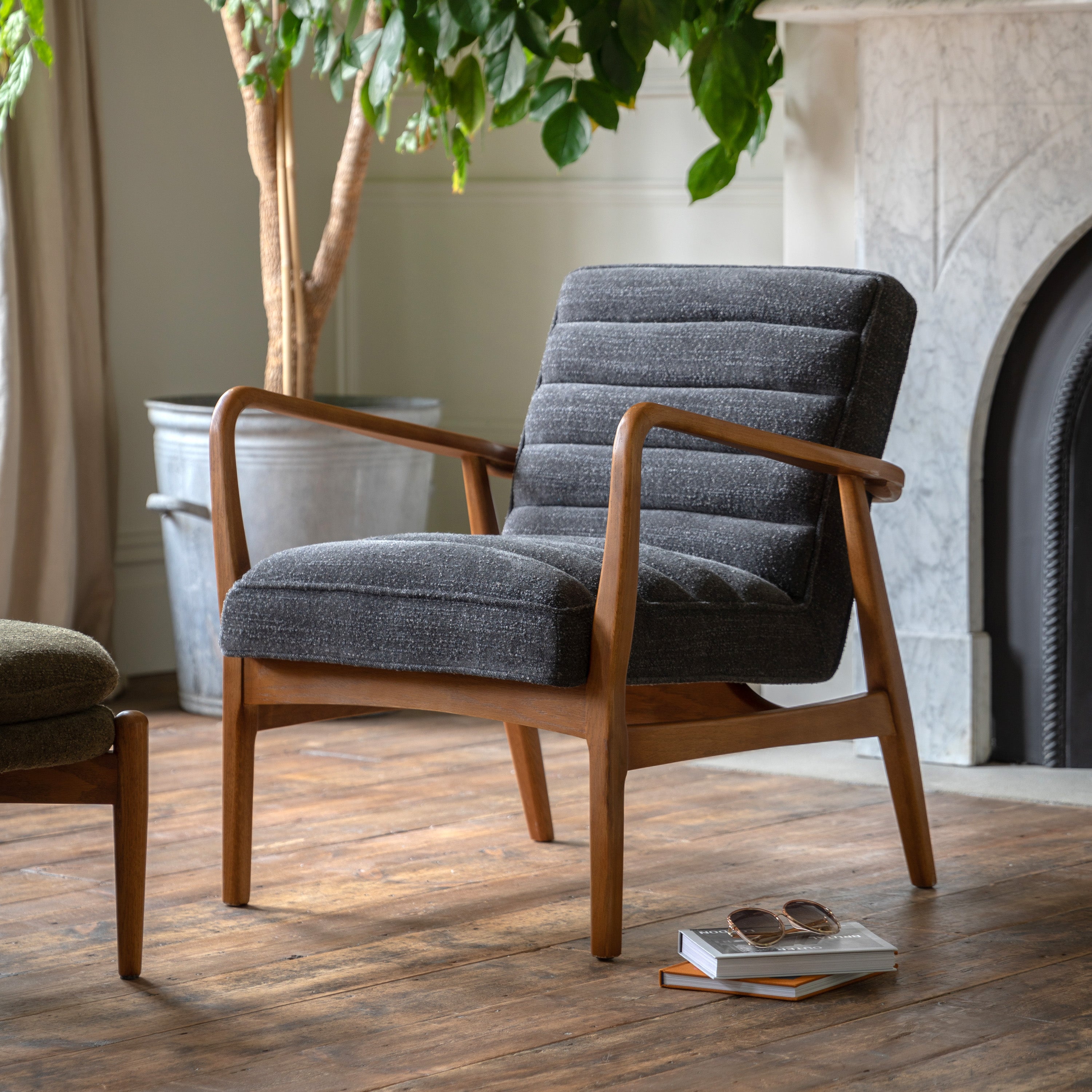 A comfortable gray upholstered armchair with a wooden frame sits in a living room.