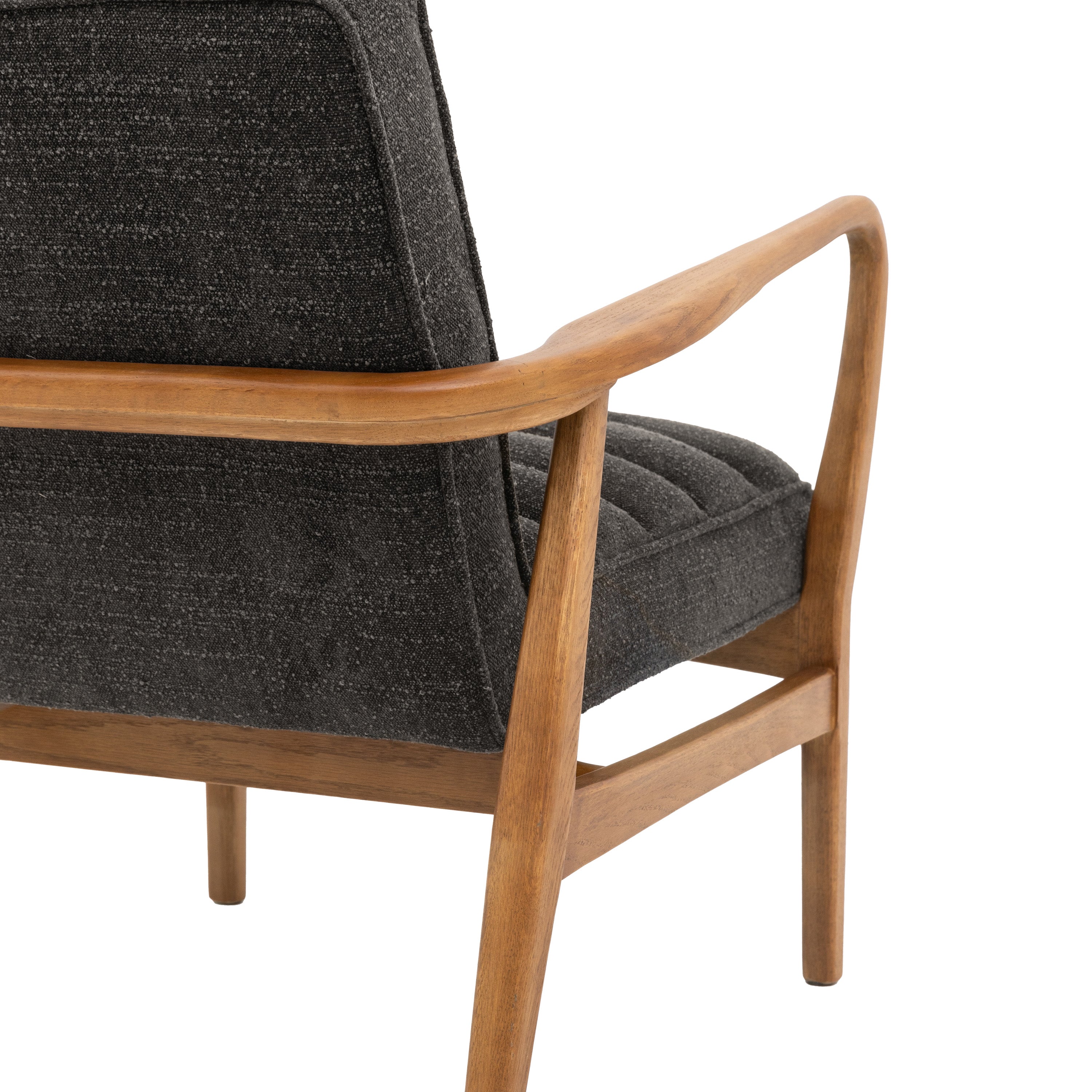 Close-up of the curved wooden armrest and side of a gray upholstered armchair.