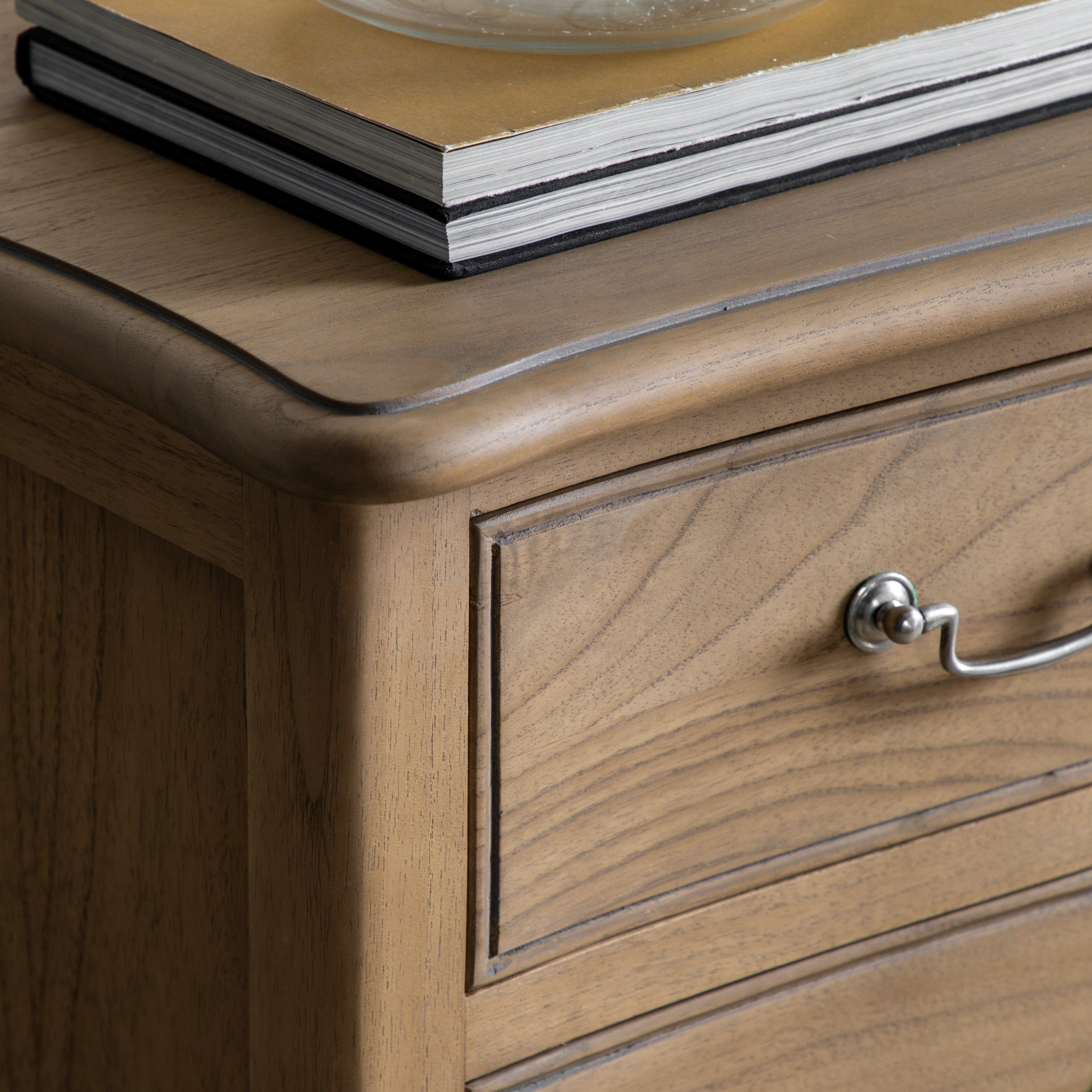 The upper right corner of a light wood chest of drawers with a book on top.