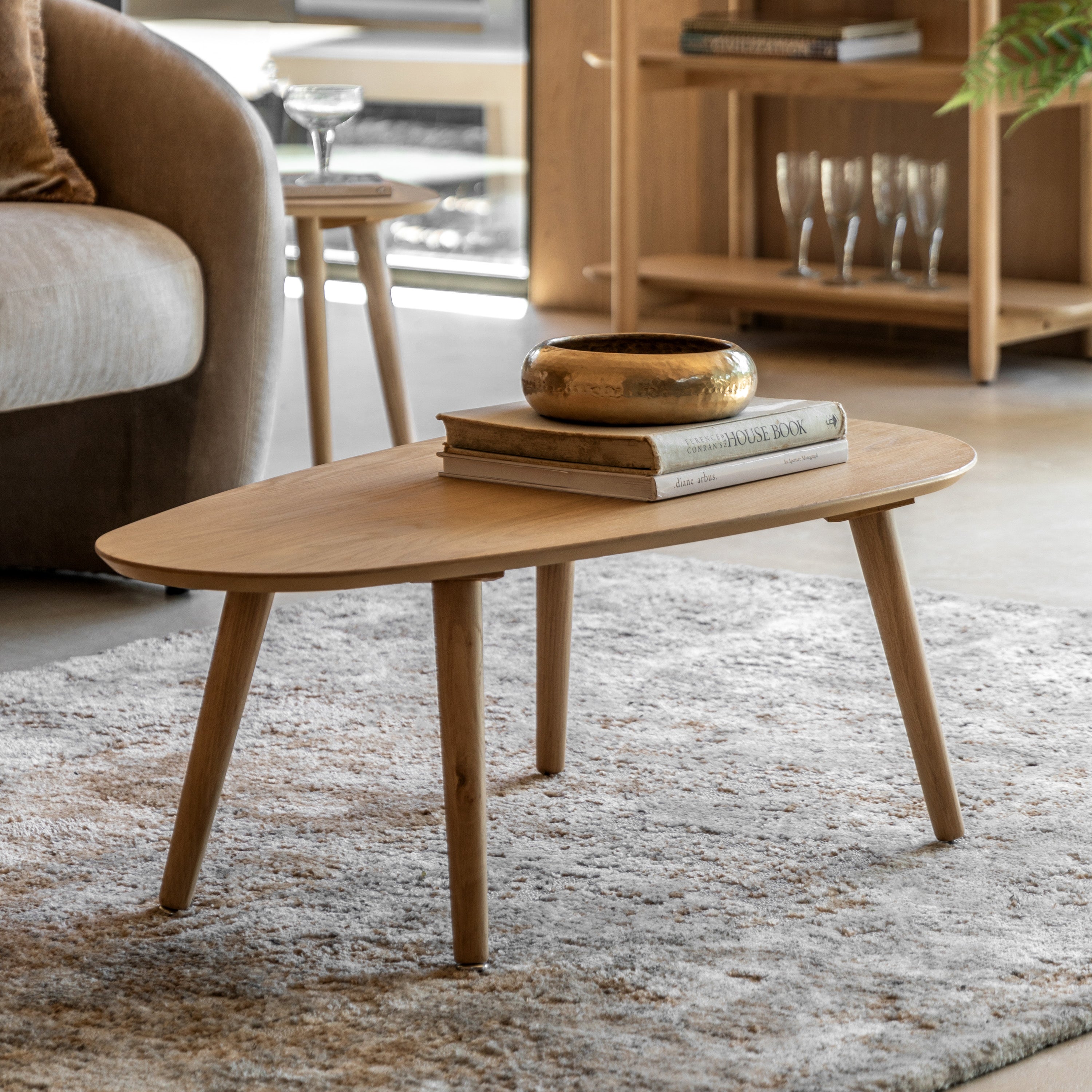 Light wooden coffee table with a gold bowl and books, adding warmth to a modern living room.
