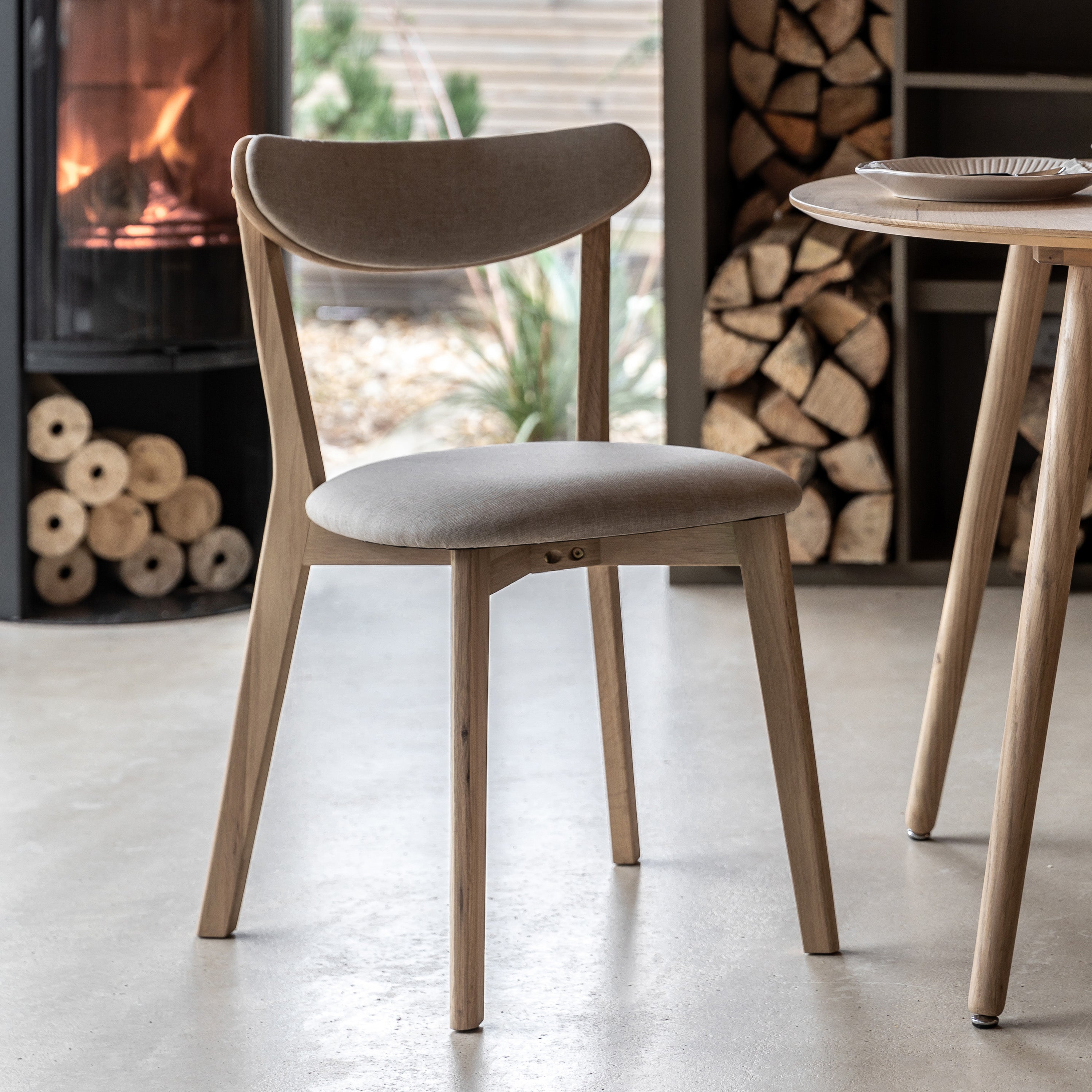 A close-up of a light wood dining chair with a grey upholstered seat and back.