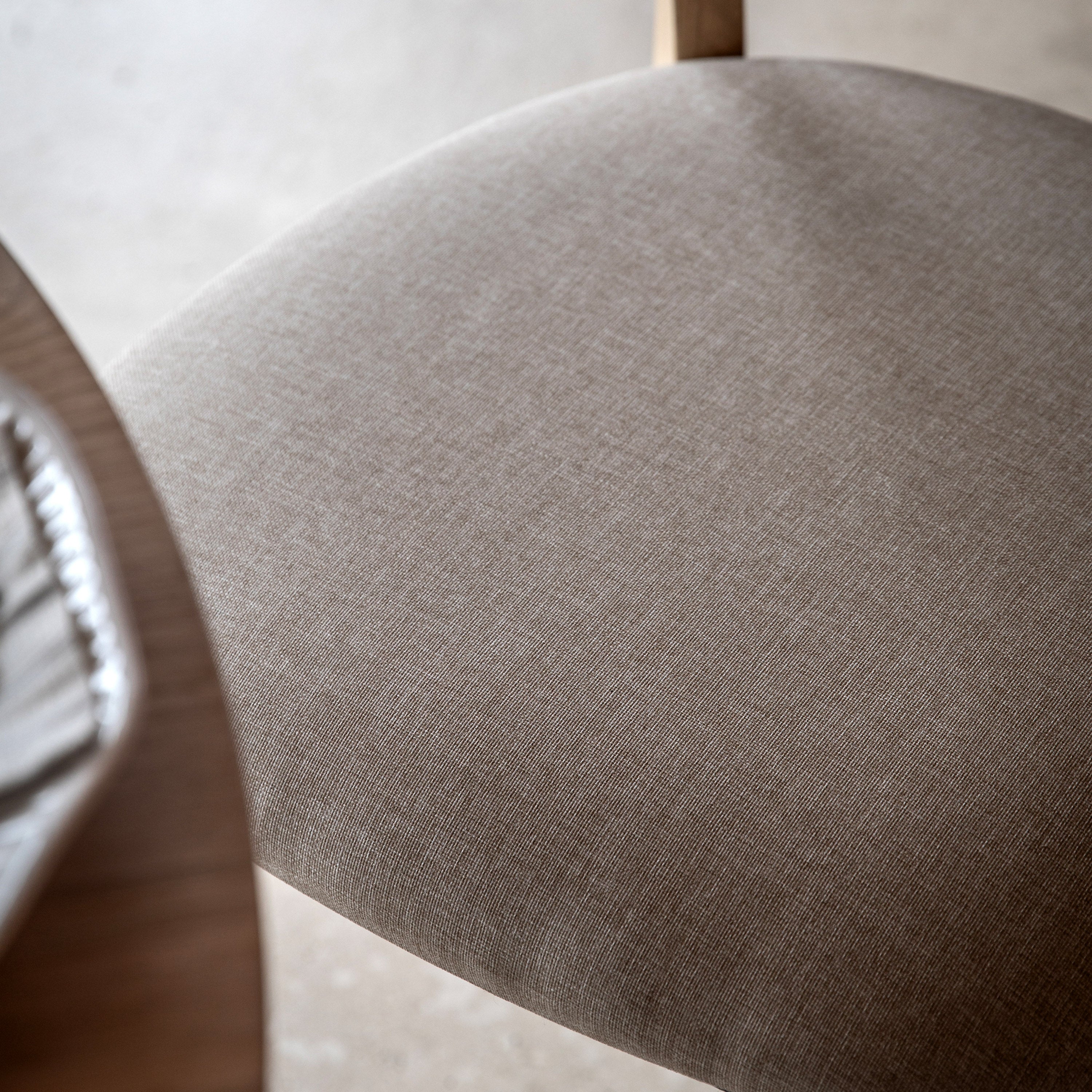 A close-up of the texture of a grey upholstered dining chair seat.