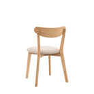 A back view of a light wood dining chair with a cream upholstered seat and back.