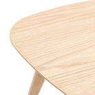 Close-up of the smooth, light wood grain of a triangular table surface.