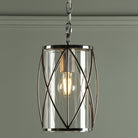 A close-up of a pendant light with a clear glass shade and a polished nickel frame.
