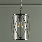 A close-up of a pendant light with a clear glass shade and a polished nickel frame.