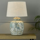 A decorative ginger jar lamp base with a neutral linen lamp shade in a living room.