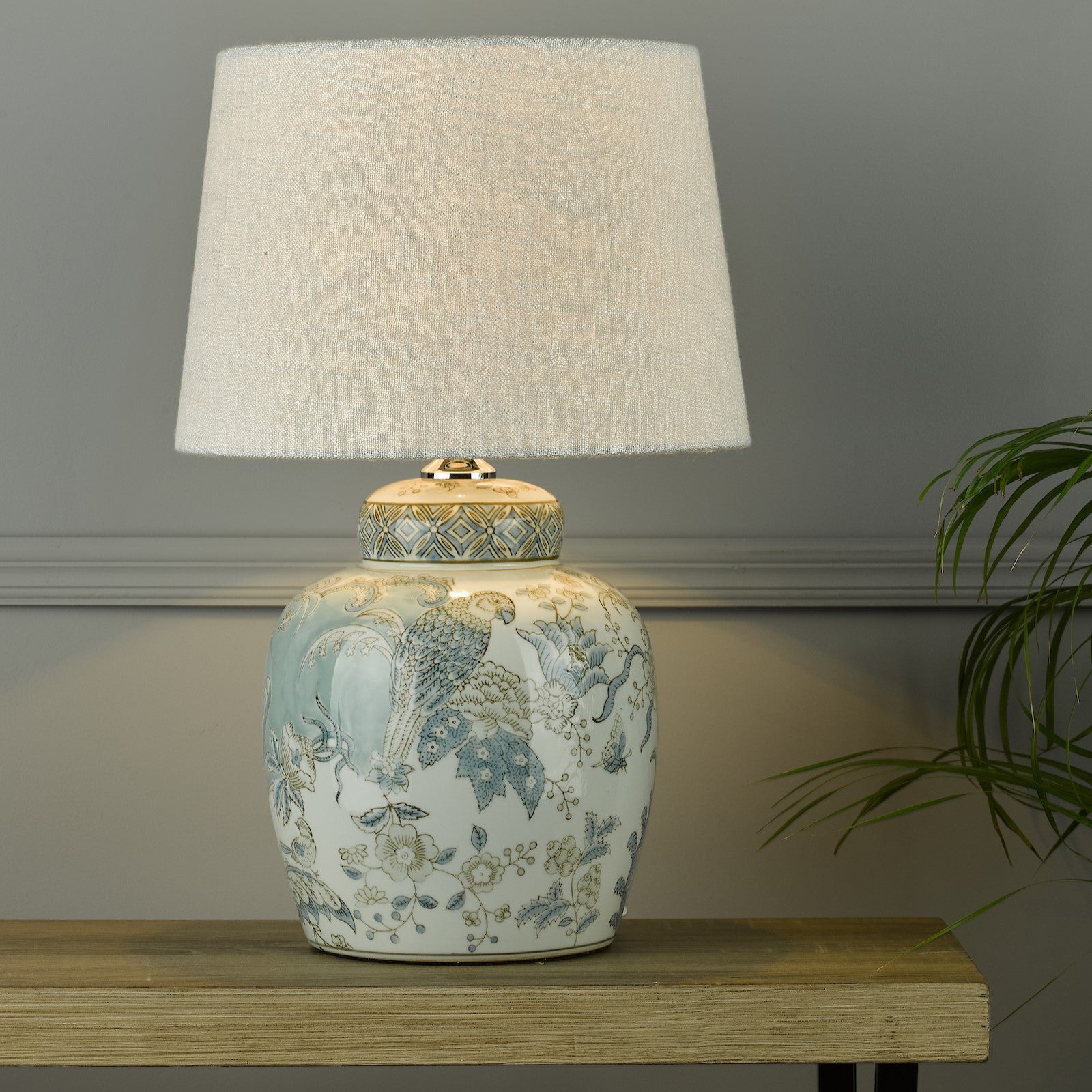 A decorative ginger jar lamp base with a neutral linen lamp shade in a living room.