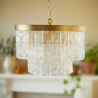 A close-up of a two-tiered glass chandelier with a brass ring, unlit.