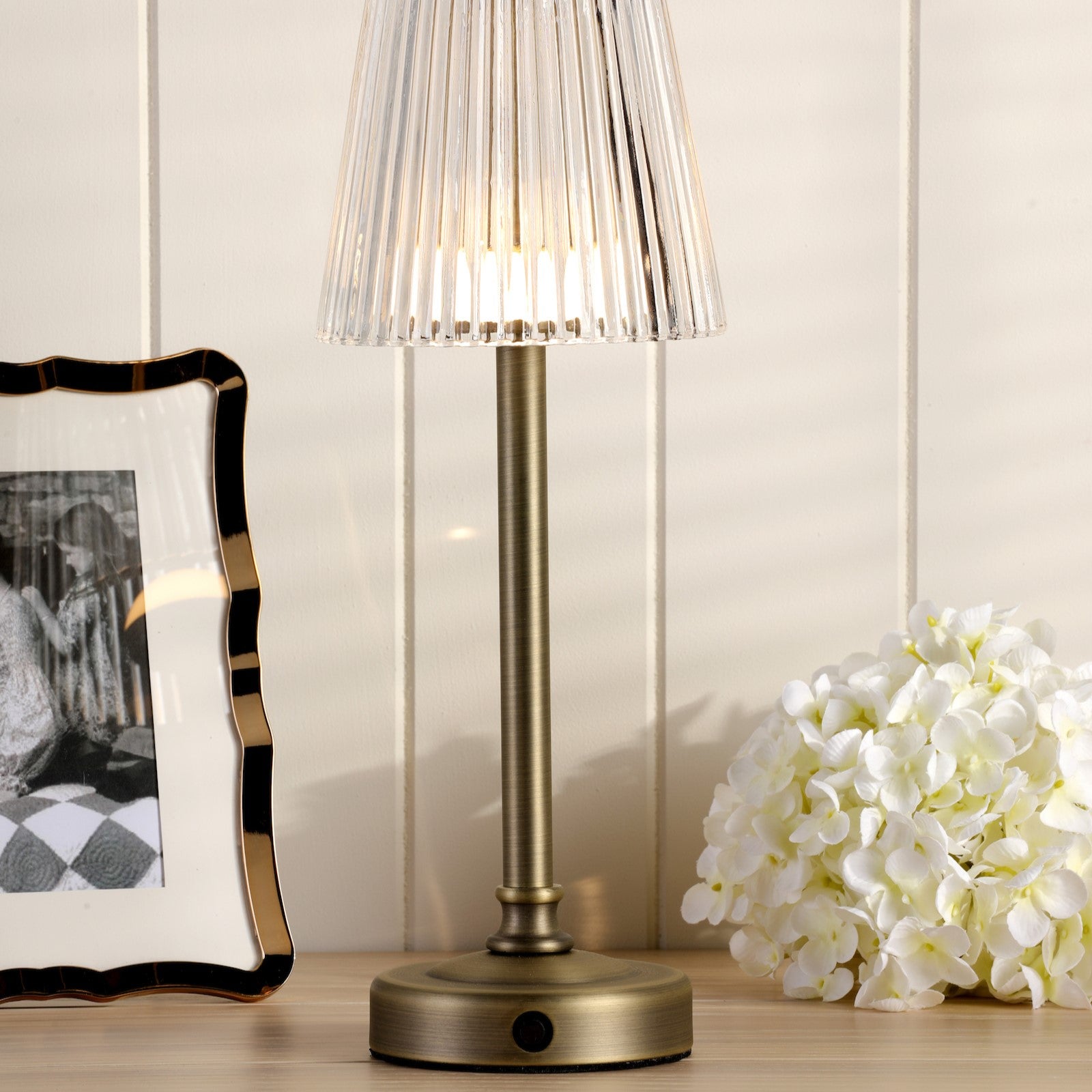 Bronze rechargable table lamp with a pleated clear plastic shade.