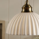 Close-up of an ivory ribbed ceramic dome shade with a brass fitting.
