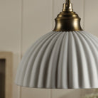 Close-up of a white ribbed ceramic dome shade with a brass fitting.