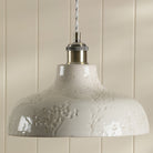 Close-up of a white textured pendant light fixture with a polished brass accent.