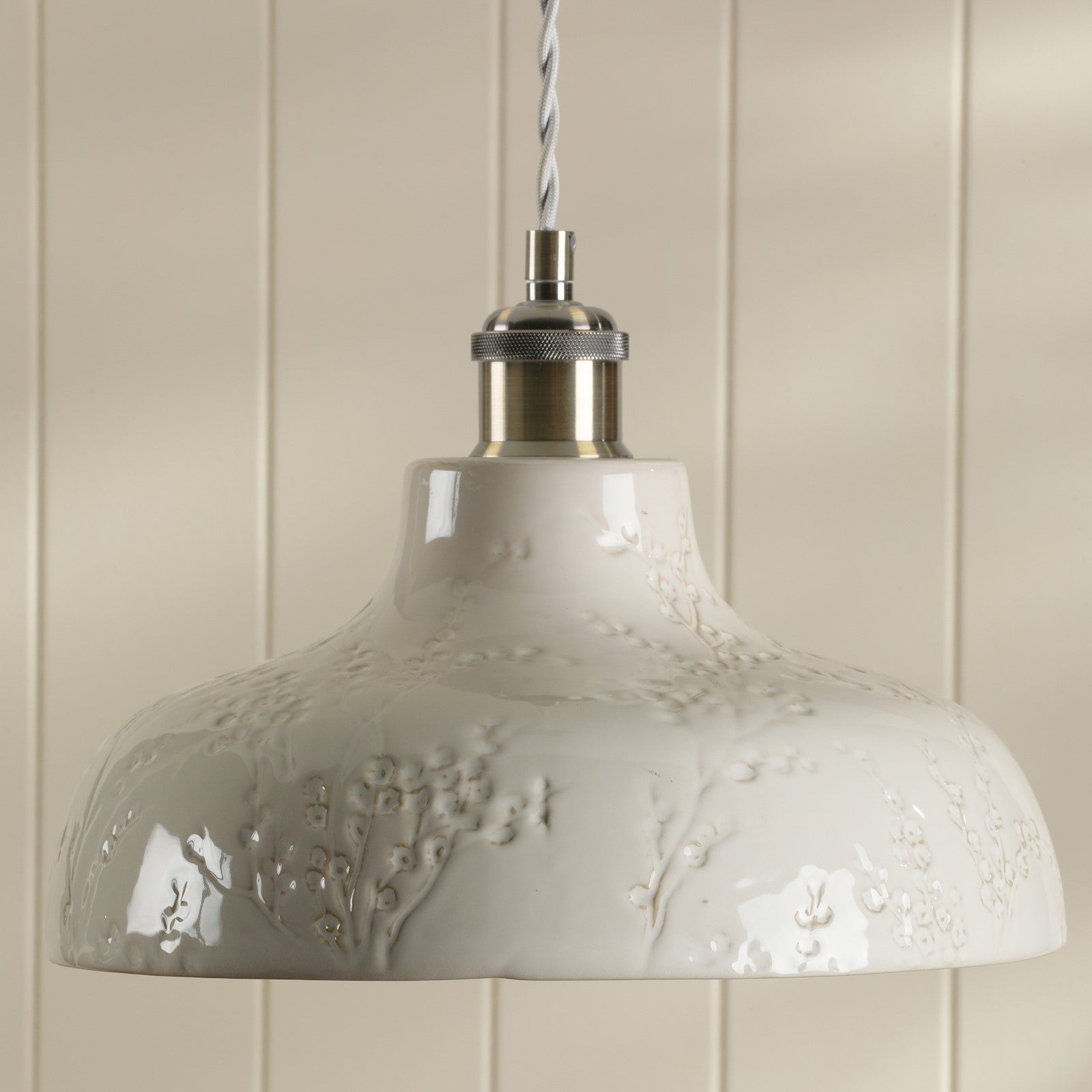 Close-up of a white textured pendant light fixture with a polished brass accent.