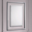 Ornate silver rectangular mirror with a smaller inner mirror, angled on a white wall.