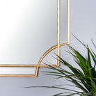 A close-up view of the ornate gold frame and curved details of the mirror.