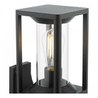 Close-up of a black outdoor wall light showing the LED filament bulb glowing softly.