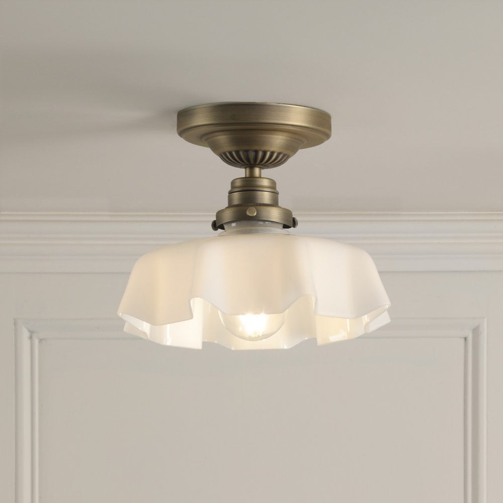 A brass ceiling light with a translucent ruffled glass shade, illuminating a soft glow.