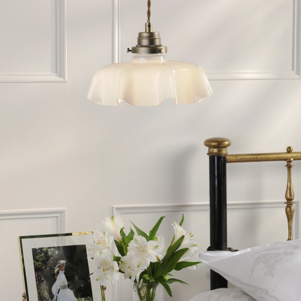 A vintage-style pendant light with a fluted white shade illuminates a bedroom.