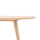 Close-up of the smooth, rounded edge of a light wooden table top and a tapered leg.