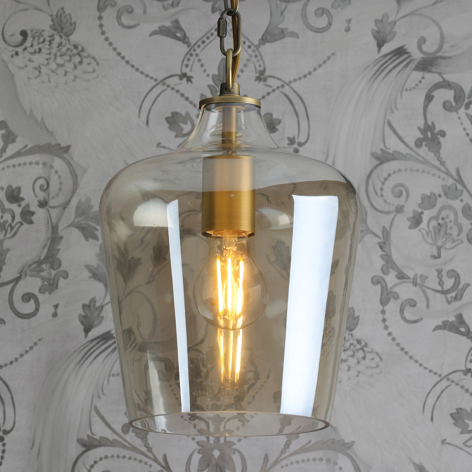 A close-up view of the pendant light with the bulb illuminated.